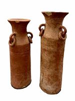 Front view of the two terra-cotta planters showing cylindrical shape, ring handles, and surface wear.