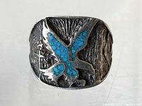 Front view showing detailed eagle design with turquoise inlay on sterling silver ring.