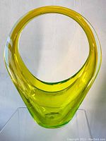 Front view of tall yellow-green uranium glass basket vase with rounded open handle top