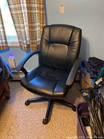 Full view of black leather feel desk chair showing seat, armrests, and five-legged base with casters.