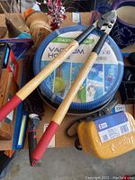 Photo showing the SwimWorks vacuum hose, metal clippers, yellow sponges, and other miscellaneous items on a table.