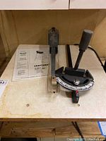 Sears Craftsman 16 inch scroll saw with adjustable miter gauge and clear blade guard visible, alongside owner's manual.