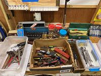 Shows various screwdrivers, sockets, and miscellaneous tools in a box on table