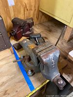 Front view showing large grey bench vise with swivel base mounted on plywood