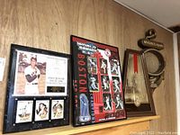 Four wall art pieces displayed together on a shelf against wood panel wall, including a Boston Red Sox World Series poster, Ted Williams plaque, Michelob Light mirror and Myers Rum mirror with nautical theme.