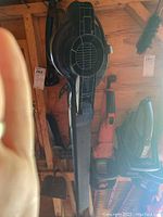 Photo showing Toro leaf blower hanging on wooden wall with nozzle and black bag attachment