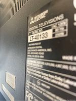 Close-up of Mitsubishi Electric digital television model label showing model LT-40133 and certification details.