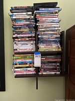 Stack of assorted DVD cases showing a wide variety of movie titles stacked on a shelf.