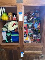 Cabinet with assorted collectibles including boxed toy cars, plush toy, candles, and other items.