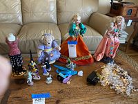 Wide view showing dolls, teddy bear, mannequin, various figurines, toy glasses, and string lights on a wooden table in front of a couch