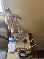 Elvis Presley figurine microphone on stand with coiled cord and a telephone handset on a surface.