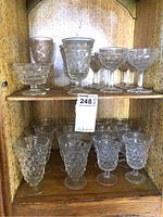 Shelf with 13 various Forstoria Early American pattern glasses, including goblets and stemmed dessert cups.