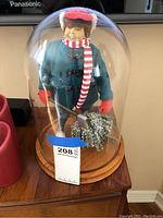 Full view of the collectible child sculpture under glass dome on a wooden base, showing overall condition and display.