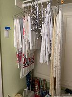 White and cream hanging fabric items including a lace panel, knit fabric, and some patterned linens on hangers