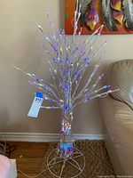 Full view of metal light tree showing spread branches, LED lights lit in multiple colors, remote control functions and timer noted in listing but not shown.