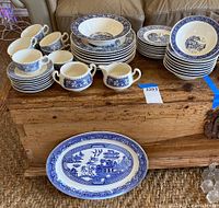 Full set displayed on wooden chest, various plates, cups, saucers, and serving pieces visible