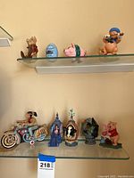 Photo of multiple animated children's story figurines on glass shelves including various animals, storybook characters, and scenes.