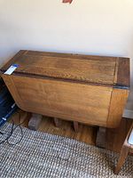 Closed gateleg table in folded position against wall, showing tabletop and side paneling.