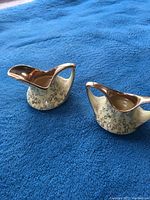 Photo of two ceramic pieces in the set, showing gold accents and floral designs.