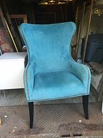 Front view of the blue wingback chair showing the upholstery and nailhead trim detail.