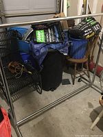 Full view of the metal clothes rack with some items around it, showing structure and condition.