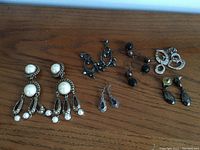 Photo of multiple pairs of earrings and bracelets on a wood surface