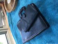 Black laptop bag with handle, showing front and top in an angled view
