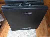 Front view of black Pilates North folding gym mat with handle.