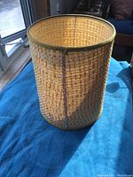 Side view photo of the orange woven lamp shade illuminated by natural light showing texture and color.