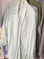 Four men's dress shirts hanging, different colors and checkered patterns visible, size extra large.