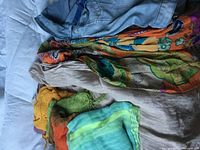 Photo showing several colorful scarves and part of a jacket laid out flat.