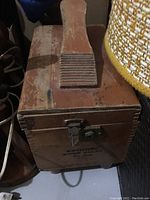 Photo showing top and front of the wooden shoe cleaning cabinet, including handle and latch, with visible wear and marks.
