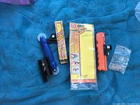 Photo showing all items including Versa-Tool Pro tile cutter in packaging, handheld blue glass cutter, orange cutter tool and bag of parts.
