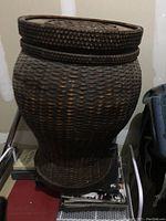 Wicker basket with lid sitting on a surface, showing its woven texture and shape.