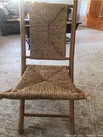 Close-up view of the bamboo folding chair showing the woven rush seat and back in a geometric design.