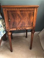 Front view of the solid wood nightstand showing cabinet door with carved geometric pattern, legs, and carved details.