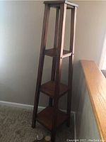 Full view of the wooden tower shelf showing its tapered leg design and three square shelves.