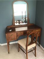 Vanity dresser with attached mirror showing full front view, highlighting wood finish and drawer layout.