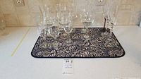 Set of 13 clear stemware glasses displayed on a patterned mat, including 7 wine glasses and 3 champagne flutes.