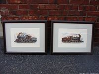 Two framed locomotive prints set against a brick wall, showing front views of both framed artworks.