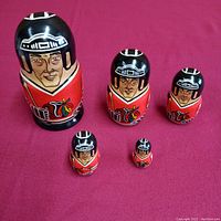 All five hand-painted wooden nesting dolls featuring NHL Chicago Blackhawks players arranged from largest to smallest on red fabric.