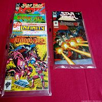 Photo of six vintage comics stacked with front covers visible, bagged for protection, showing Bloodshot, Star Trek, Batman Annual Bloodlines and more.