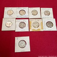 Front side of nine Washington quarter dollar coins in holders, showing obverse with dates and mint variation notes.