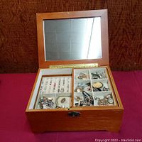 Front view of wooden jewelry box with mirror lid open showing ring tray and 8-compartment tray