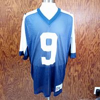 Front view of navy blue Reebok Dallas Cowboys jersey with number 9, showing mesh texture and V-neck collar.