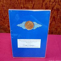Blue display case front with centered 23 karat gold enhanced coin and signed limited edition label.