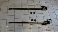 Overview photo showing two pairs of black carbon fiber hiking poles with wrist straps and removable snow baskets, laid on tile floor