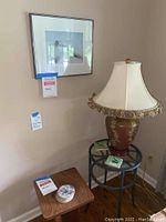 Overall view of wood and metal/glass end tables, lamp on metal/glass table, signed framed print above, and 7 coasters on tables.