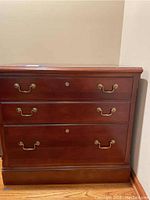 Front view of the lateral file cabinet showing three drawers with brass handles and lock keyholes.