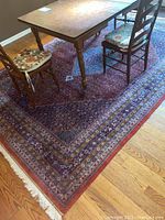 Overall view of rug laid under dining table and chairs showing full pattern and color.
